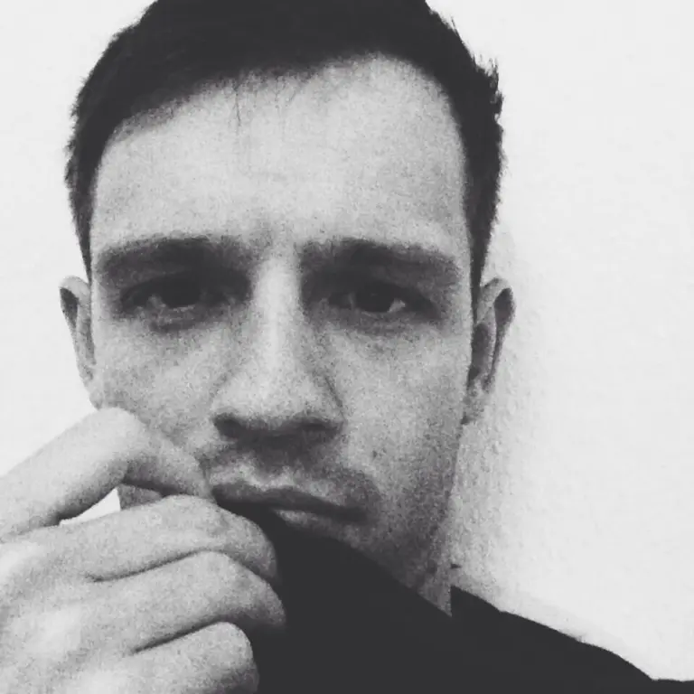 Andreas mit dunklem Haar und nachdenklichem Gesichtsausdruck, Hand ans Kinn gelegt, schwarz-weiße Porträtaufnahme.